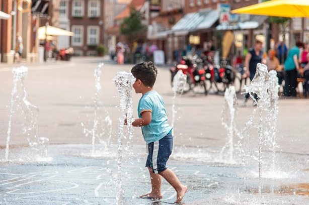 Ein Kind spielt auf dem Brunnen auf dem Marktplatz in Meppen. © Schöning Fotodesign
